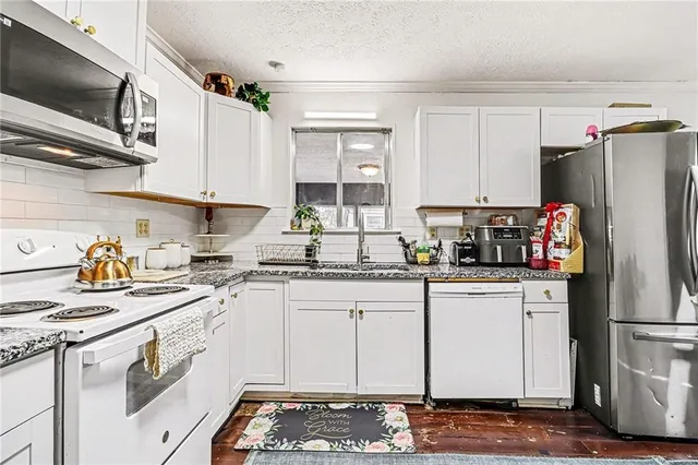 a kitchen with stainless steel appliances granite countertop a refrigerator sink stove microwave and cabinets