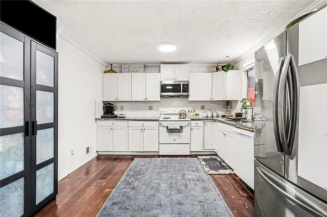 a kitchen with granite countertop a refrigerator stove top oven and sink