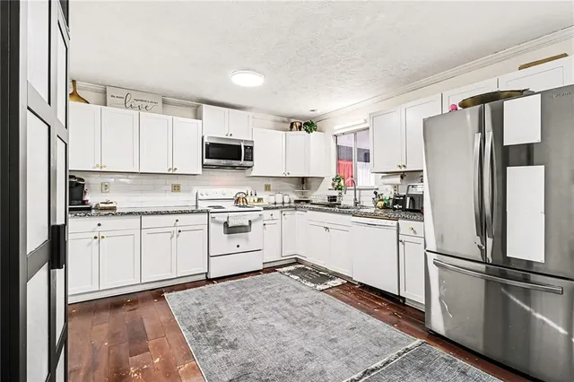a kitchen with granite countertop a refrigerator stove top oven and sink