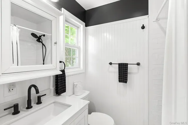 a bathroom with a sink and mirror with toilet