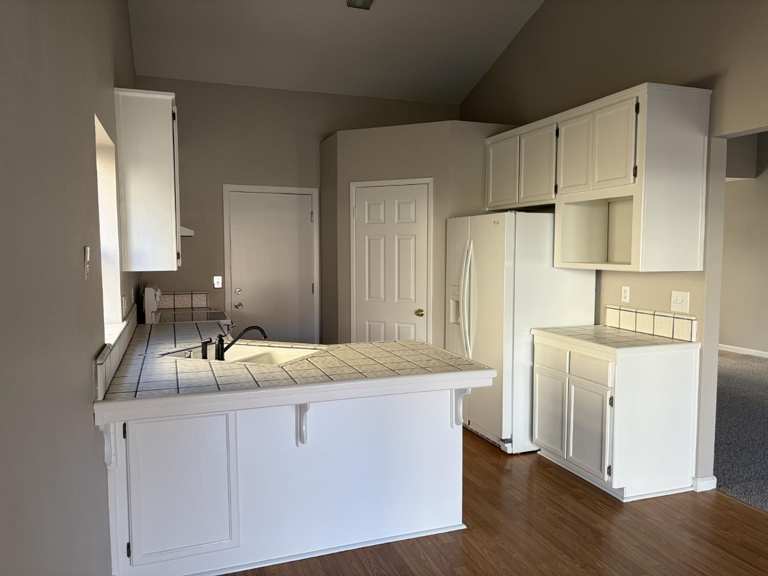 2401 Walnut Grove Way Modesto, CA 95355 - Photo 8 of 25 a room with kitchen island granite countertop white cabinets white stainless steel appliances and wooden floor