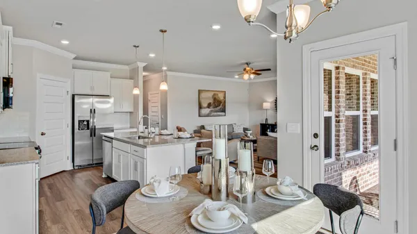 a kitchen with stainless steel appliances kitchen island granite countertop a refrigerator a stove a dining table and chairs with wooden floor