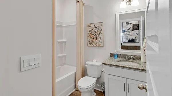 a bathroom with a granite countertop toilet a sink and a mirror