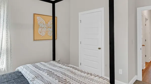 a view of a bedroom with a bed and wooden floor