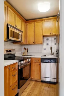 a kitchen with stainless steel appliances granite countertop wooden cabinets stove top oven a sink and dishwasher with wooden floor