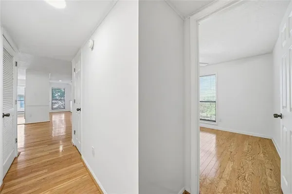 a view of a hallway with wooden floor and a bathroom