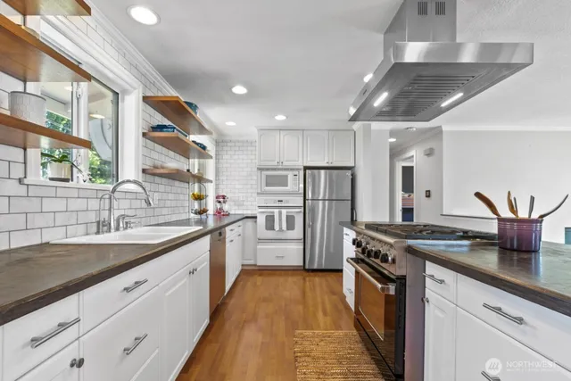 a kitchen with stainless steel appliances granite countertop a sink a stove and a wooden floors