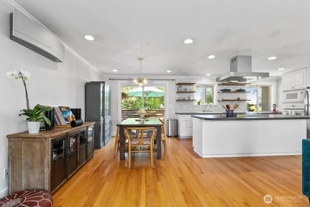 a kitchen with stainless steel appliances granite countertop wooden floor a stove top oven a sink with dining table and chairs