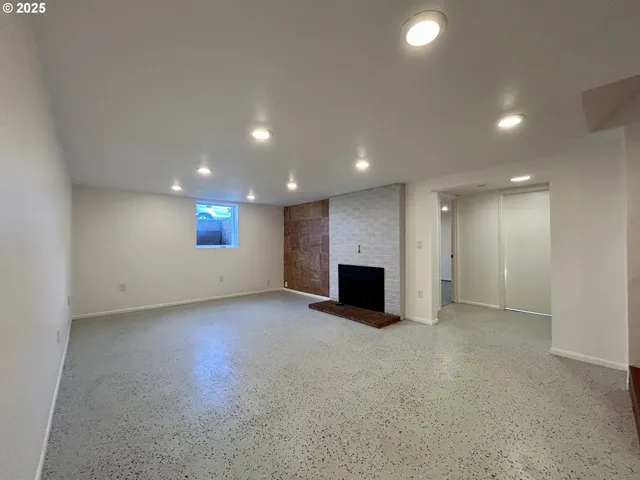 an empty room with windows and fireplace