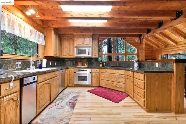 a kitchen with stainless steel appliances granite countertop a refrigerator a stove a sink and dishwasher with wooden floor