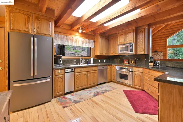 a kitchen with granite countertop a refrigerator a sink dishwasher a stove and white cabinets with wooden floor