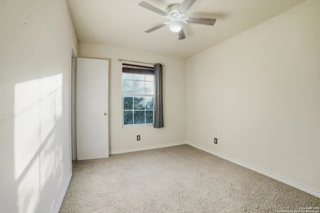 an empty room with a window and a fan