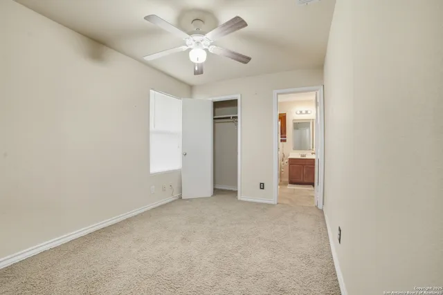 an empty room with a ceiling fan and a bathroom