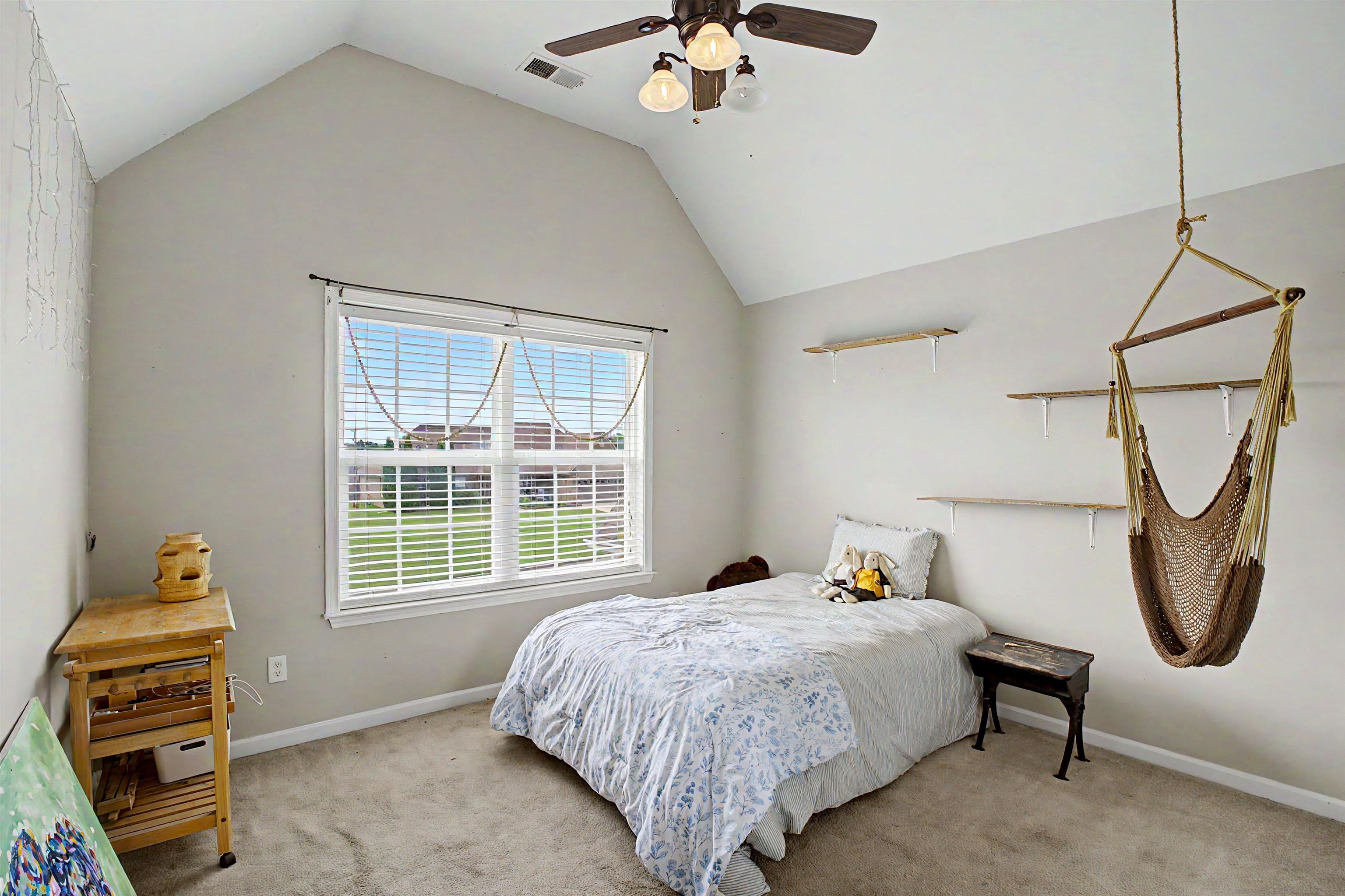 134 Rembert Drive Atoka, TN 38004 - Photo 29 of 38 Room featuring a vaulted ceiling with a ceiling fan, a large window with horizontal blinds, neutral wall paint, and soft carpet flooring