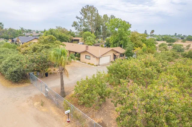 an aerial view of a house with a yard and greenery