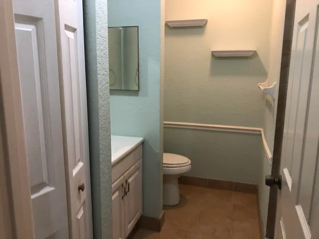 a bathroom with a granite countertop toilet and a sink