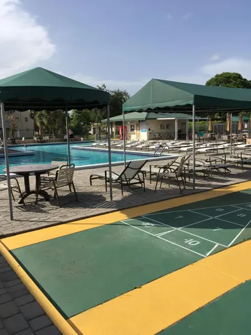 a view of a swimming pool with lawn chairs under an umbrella
