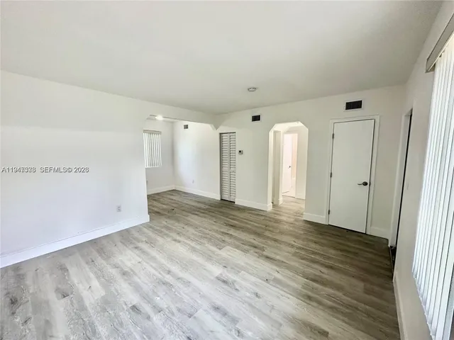 a view of an empty room with wooden floor