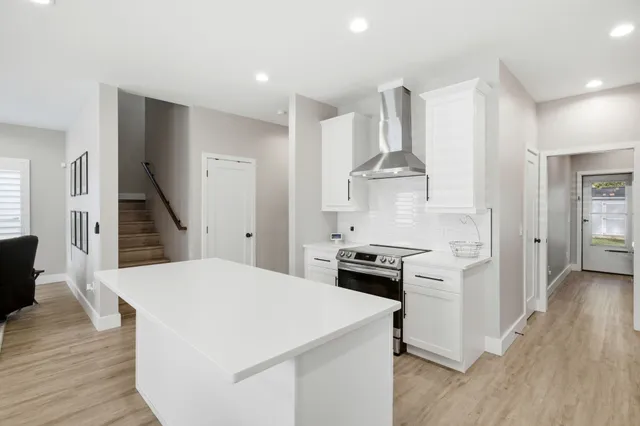 a kitchen with stainless steel appliances a stove a refrigerator and a view of living room