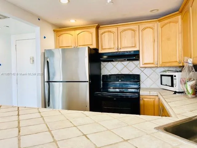 a kitchen with granite countertop a refrigerator and a stove top oven