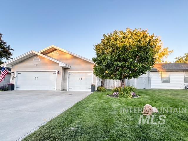 808 O'Leary Way Twin Falls, ID 83301 - Photo 28 of 37 Light-colored siding exterior featuring two garage doors, a concrete driveway, and a manicured lawn with a mature tree