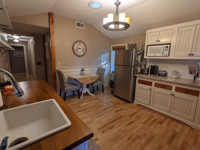 a kitchen with stainless steel appliances granite countertop a refrigerator a stove a sink dishwasher and a dining table with wooden floor