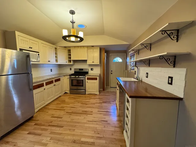 a kitchen with stainless steel appliances granite countertop a refrigerator a stove and a sink
