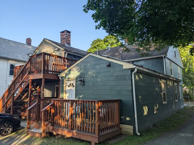 a view of a brick house with a small yard and a large tree