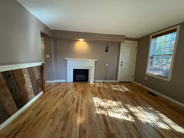 a view of empty room with wooden floor and fireplace