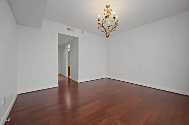 a view of a hallway with wooden floor and a chandelier
