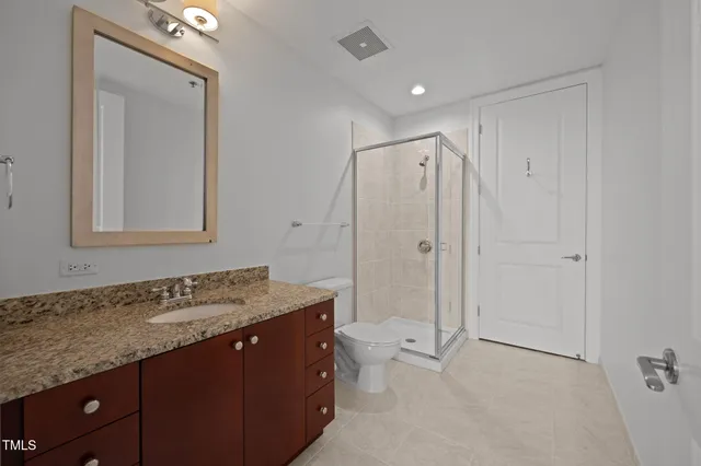 a bathroom with a granite countertop sink a toilet a mirror and shower