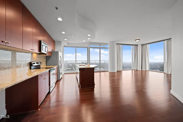 a large kitchen with stainless steel appliances granite countertop a large counter top a stove and a wooden floors