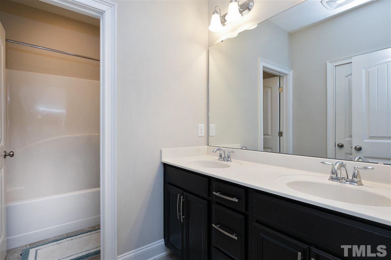 637 Fallon Grove Way Raleigh, NC 27608 - Photo 24 of 30 a bathroom with a double vanity sink a mirror and a bathtub