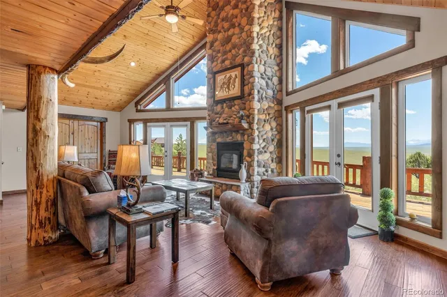 a living room with furniture a large window and wooden floor