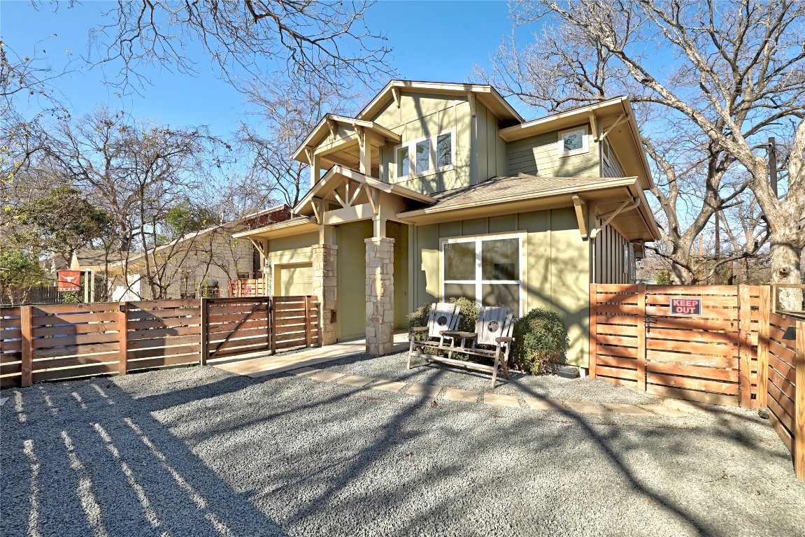 View of front of house featuring a gate, board and batten siding, and stone siding