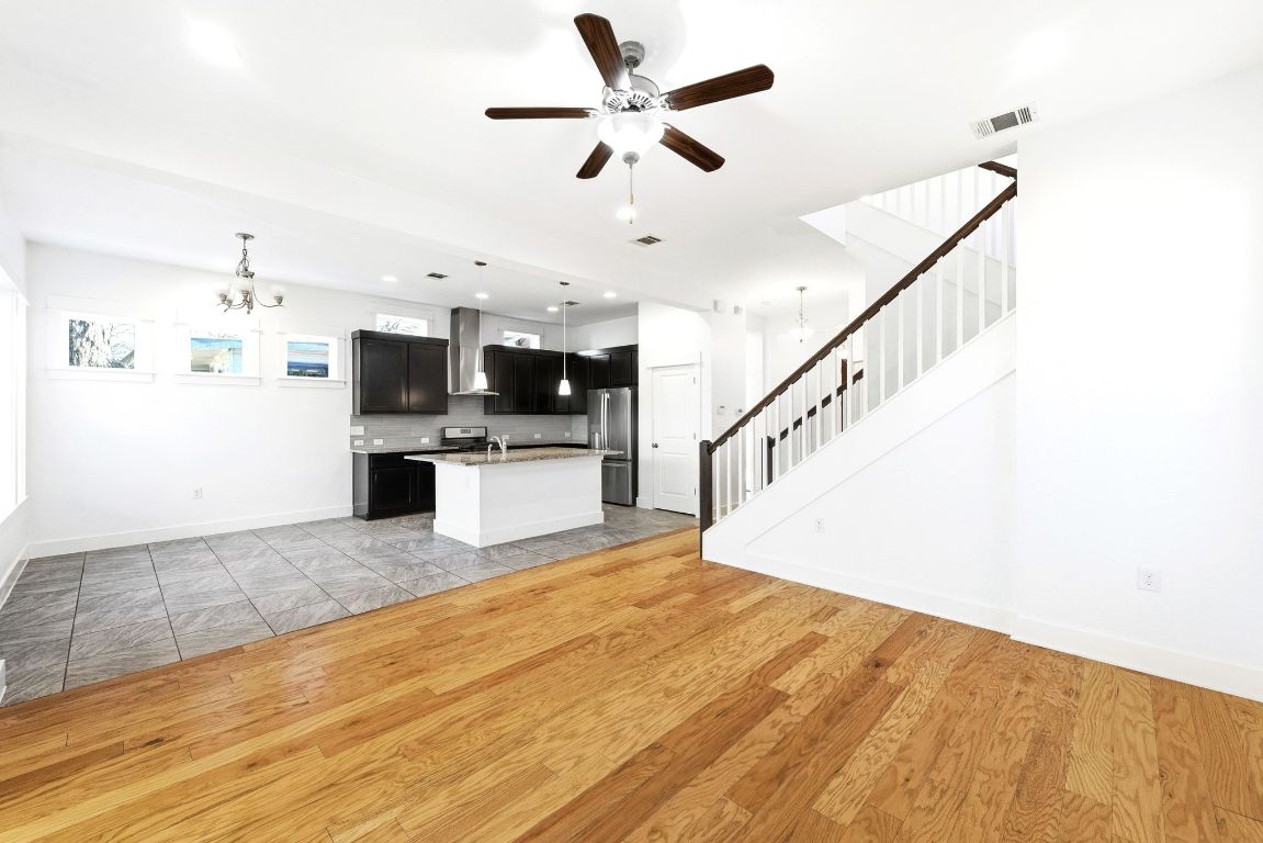 1912 Haskell Street, Unit 1 Austin, TX 78702 - Photo 4 of 23 Unfurnished living room with a chandelier, light wood-style floors, stairway, a ceiling fan, and recessed lighting