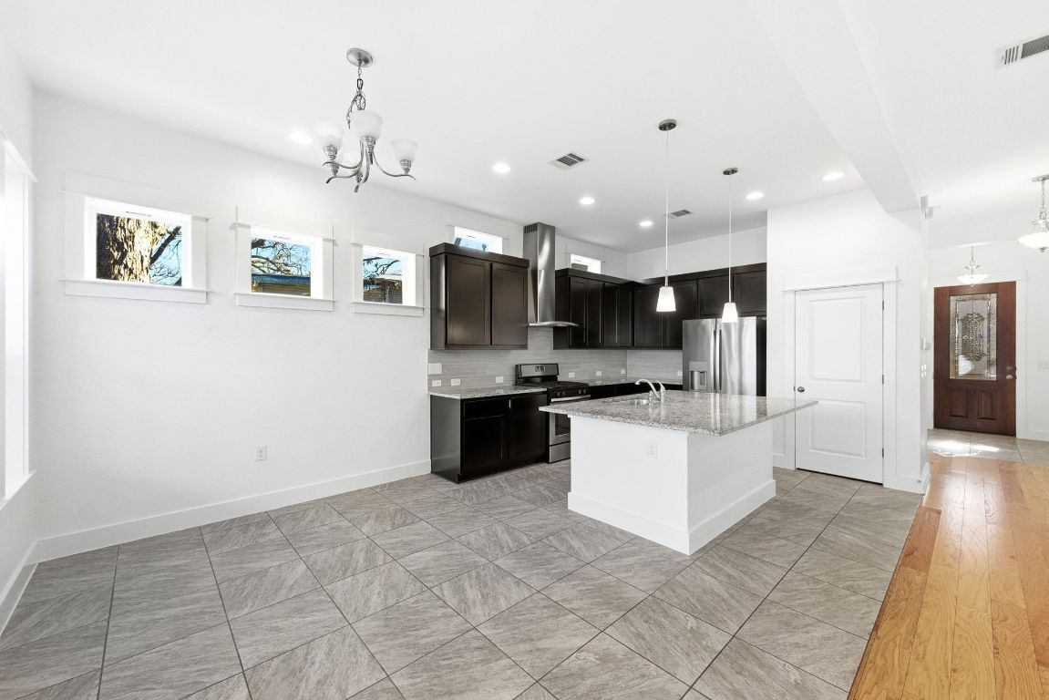 1912 Haskell Street, Unit 1 Austin, TX 78702 - Photo 6 of 23 Kitchen with appliances with stainless steel finishes, a center island with sink, pendant lighting, a chandelier, and recessed lighting