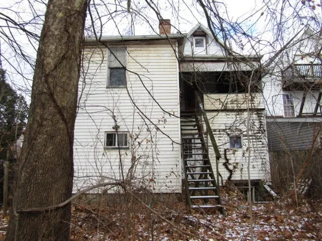 a brick house with a small yard and large trees