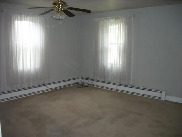 an empty room with windows and chandelier fan