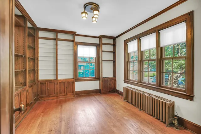 a view of an empty room with wooden floor and a window