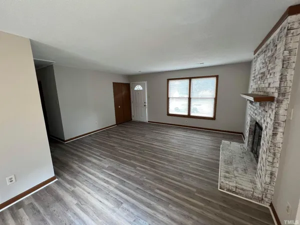 an empty room with windows and fireplace