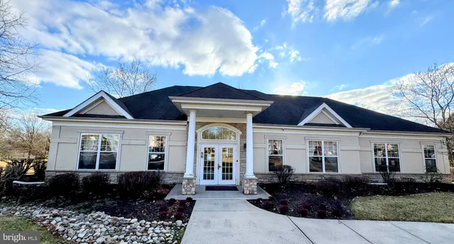 a front view of a building with lot of cars and trees