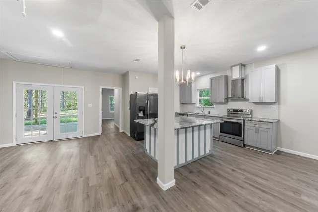 a kitchen with stainless steel appliances a stove top oven a sink dishwasher and a refrigerator with wooden floor