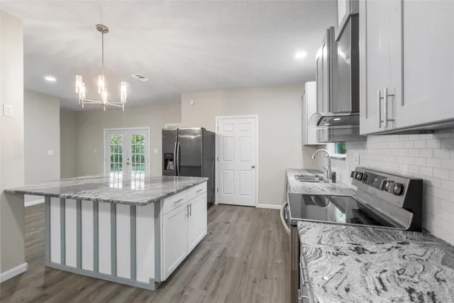 a kitchen with granite countertop a stove a sink and a refrigerator