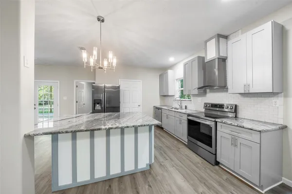 a kitchen with stainless steel appliances granite countertop a stove top oven a sink and white cabinets