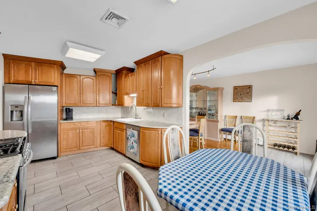 a kitchen with stainless steel appliances granite countertop a refrigerator a sink dishwasher a stove and white countertops with wooden floor