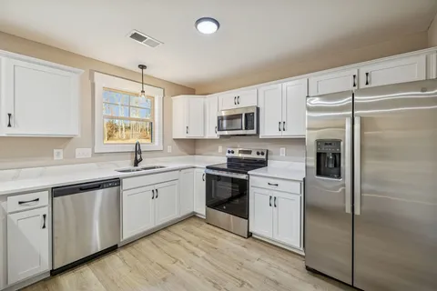 a kitchen with white cabinets and a window