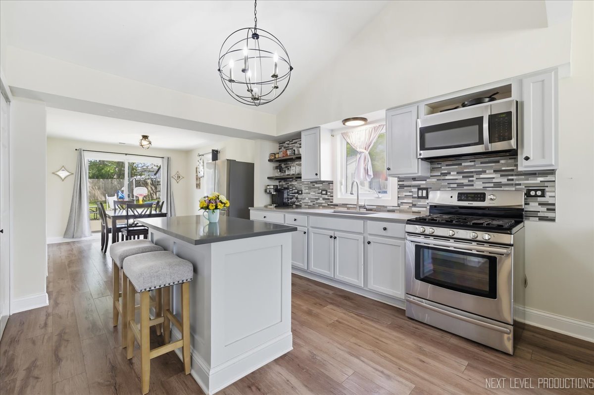 138 North Calhoun Street Aurora, IL 60505 - Photo 11 of 24 a kitchen with stainless steel appliances granite countertop a stove top oven a sink dishwasher a dining table and chairs with wooden floor