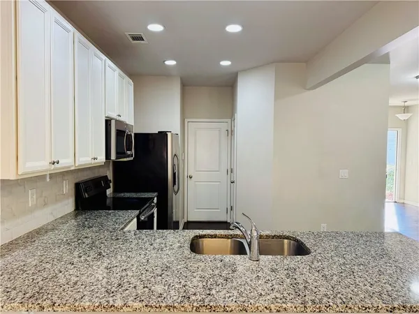 a bathroom with a granite countertop sink and a refrigerator
