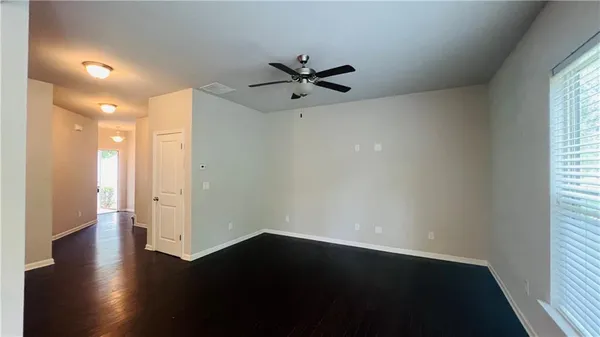 an empty room with wooden floor a ceiling fan and windows